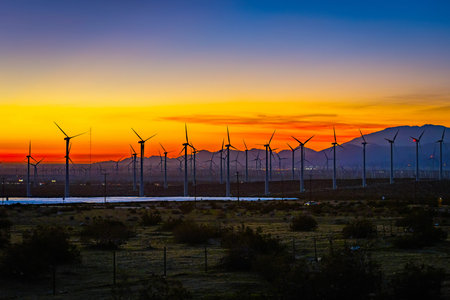 Panoramic view of a deep crimson sunset over California hills with wind turbines forming dramatic...