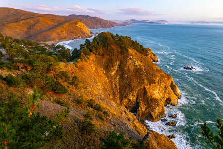 Golden sunset light reflects across ocean waves and rugged coastline at Muir Beach California