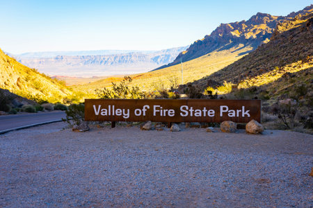 Entrance sign of Valley of Fire State Park lit by warm sunset light with desert surroundings