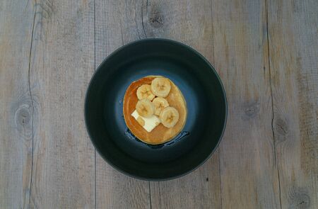 Stack of pancakes with maple syrup and bananas