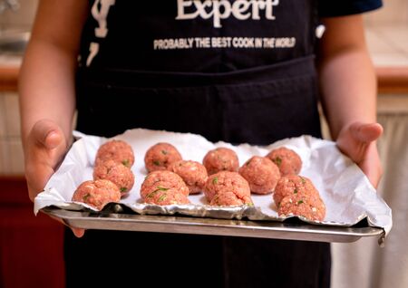 person carrying raw beef patties on the trayの写真素材