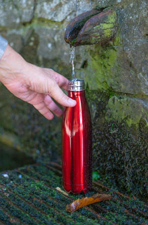 Drinking water concept. water bottle filling up at the fountain