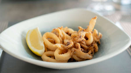 Close up of delicious crispy deep fried calamari with lemon on a white plate.の写真素材