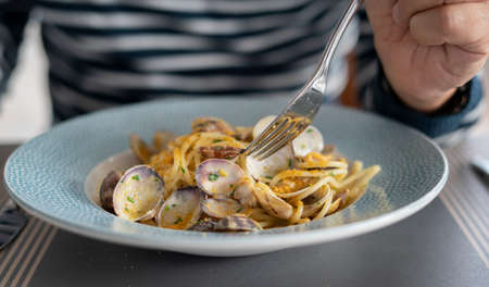 detail male hand eating pasta spaghetti with clams and mullet, Mediterranean food