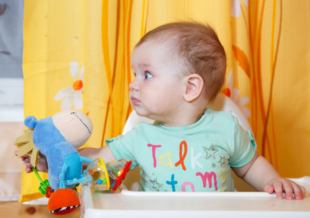 Hungry baby with toy in his hand waiting for foodの写真素材