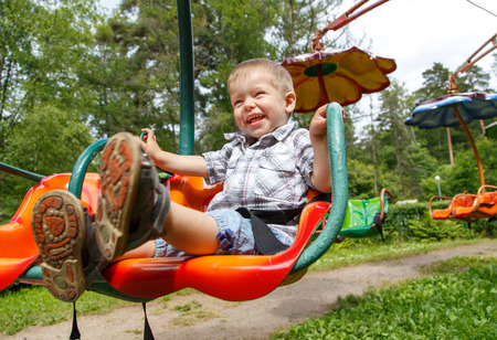 Joyful little boy having fun on carousel in the parkの写真素材