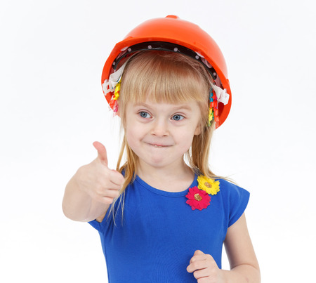 Funny little blond girl with two tails in orange helmet showing big thumbの写真素材