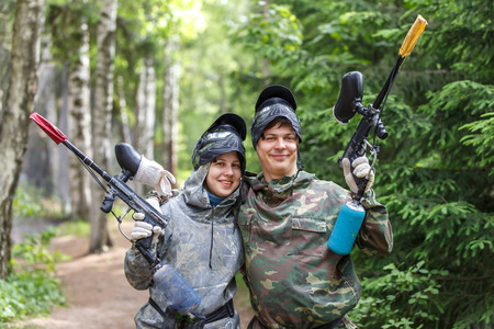 Smiling boy and girl posing with paintball markers outdoorsの写真素材