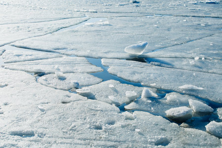 Melting ice on the lake in spring - large pieces of ice in the water in the sun - dangerous winter...