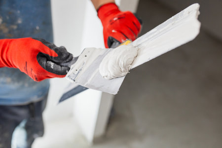 Leveling the walls with white putty - the hands of a master with a spatulaの写真素材