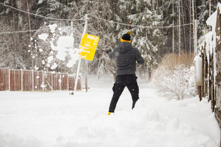 Deep drifts of snow after a heavy storm - an adult man clears the paths from snow with a shovel -...
