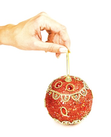 female hand holding a red Christmas ball on a stringの写真素材