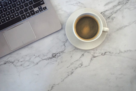 Coffee cup and laptop on white marble table, top viewの写真素材