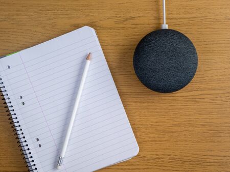 Smart home device speaker on desk table with pencil and pad of paper