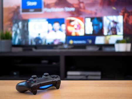 UK, Jan 2020: Sony dualshock 4 controller remote for Playstation 4 with tv screen in background