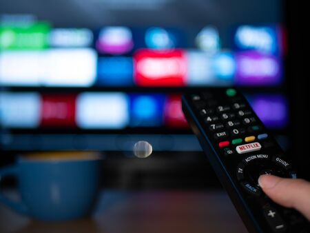 UK, Jan 2020: Netflix remote control with android apps on smart TV screen in home setting