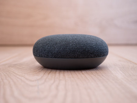close up mini smart home speaker device on wooden background with voice assistant