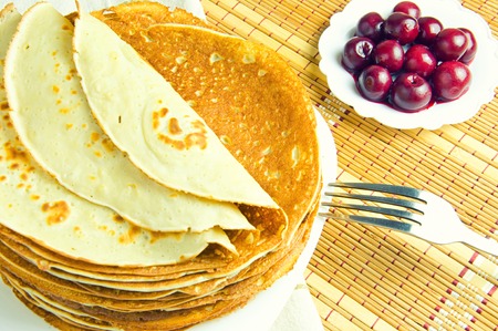 pancakes on a white plate and cherry