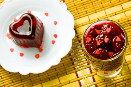 red heart cherry jelly and a glass on a bamboo napkinの写真素材