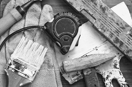 paint brush, level, hammer, putty knife stained with paint on wooden backgroundの写真素材