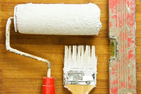 Painting tools stained in white paint on the background of wooden boards