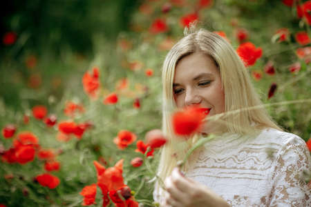 beautiful girl in a field with red poppies in a transparent bodysuitの写真素材