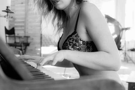 A nude beautiful sitting at a pianoの写真素材