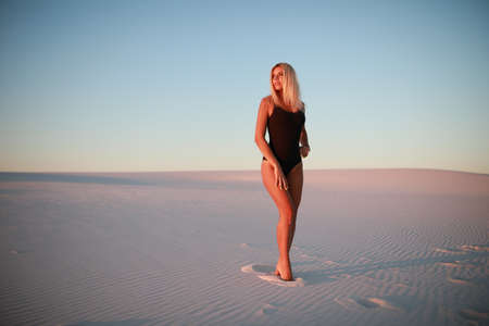 Beautiful blonde is resting on the sandy beach near the oceanの写真素材
