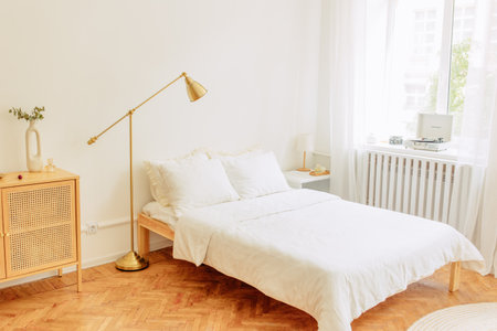 Interior of light room with bed, rattan side table and soft carpetの写真素材