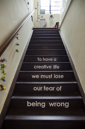 To have a creative life we must lose our fear of being wrong. Bottom view on stairs with text on stepsの写真素材