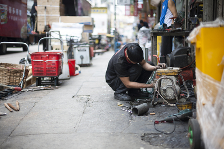 Mechanic busy with work on a narrow street in Chinaの写真素材