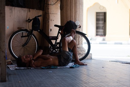 Tired asiat man sleep and relax near bicycle on the floorのeditorial素材