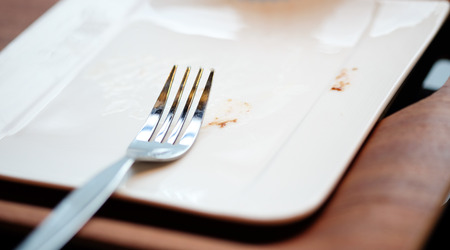 Fork on empty white dish after finish bakeryの写真素材