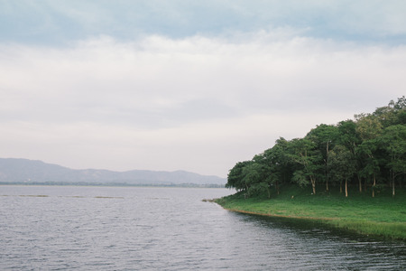 Peaceful lake and shore in cloudy dayの写真素材