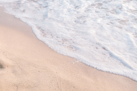 Calm sea wave with white foam on the beachの写真素材
