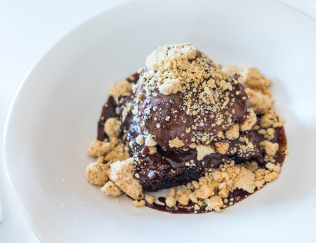 Close-up shot of brownie topped with chocolate ice-cream on white plateの写真素材