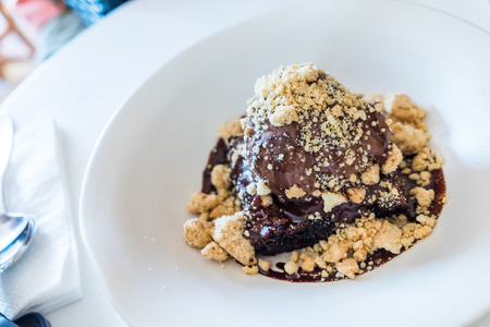 Close-up shot of brownie topped with chocolate ice-cream on white plateの写真素材