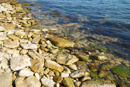 A coast with pebble and blue ocean water.