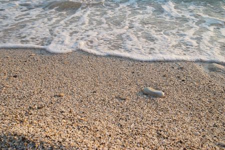 Tropical sand beach with sea waves and stones.の写真素材