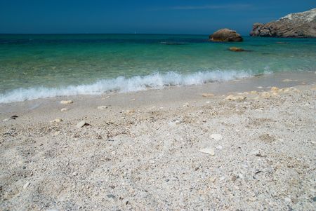 Tropical sand beach with sea waves and stones.の写真素材