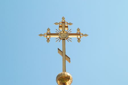 Golden orthodox cross with blue sky backgroundの写真素材