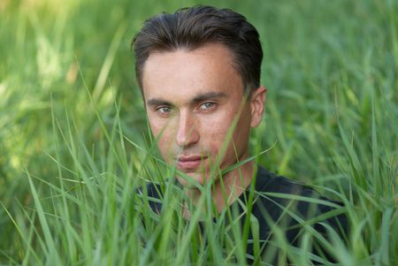 Man's portrait in the green grass backgroundの写真素材
