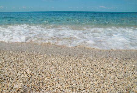 Tropical sand beach with sea waves and stones.の写真素材