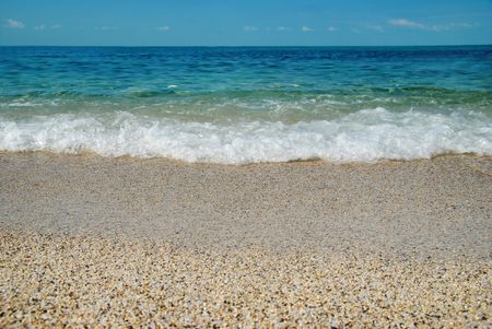 Tropical sand beach with sea waves and stones.の写真素材