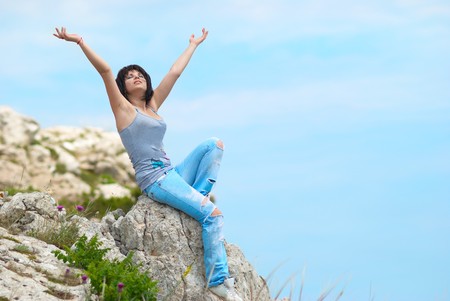 Pretty young woman relaxing on the rockの写真素材