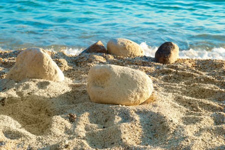Tropical sand beach with sea waves and stones.の写真素材