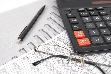 Pen, glasses and calculator on paper table with finance diagramの写真素材