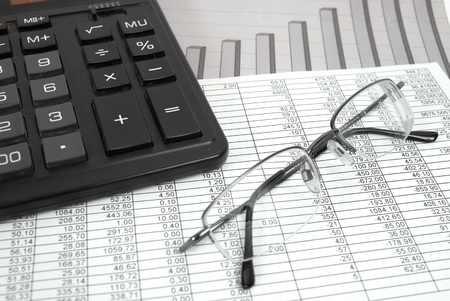 Glasses and calculator on paper table with finance diagramの写真素材