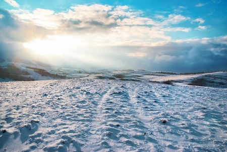 Winter hills covered by snow against sunsetの写真素材