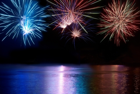 Blue, red and white colorful fireworks above the river. Holiday celebration.の写真素材